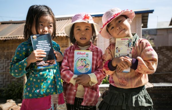 Bimbe tengono in mano volantini di sensibilizzazione sulla malaria in Myanmar. Foto di Gianfranco Ferraro.